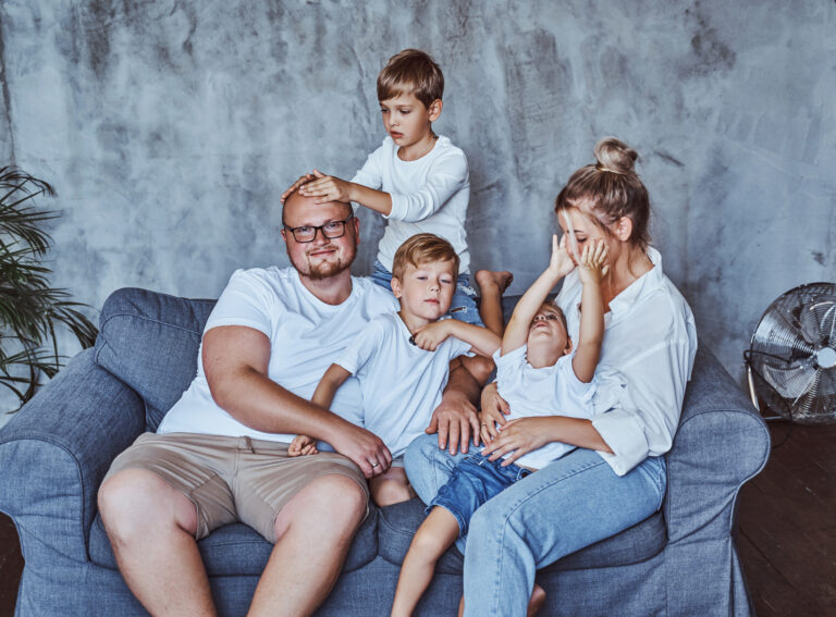 Mother and father with their boys sitting on sofa