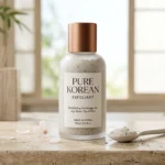Flacon d'exfoliant Pure Korean posé sur une pierre polie dans un décor minimaliste de spa coréen.